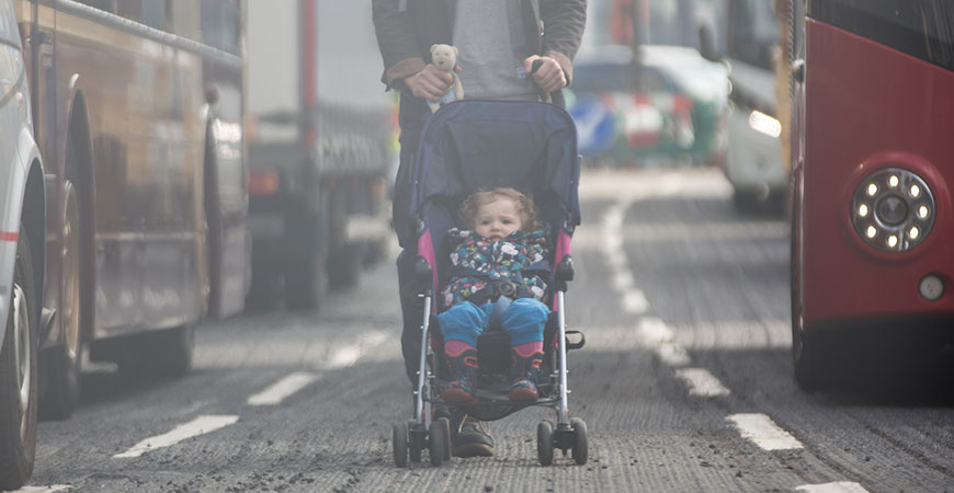 A child is surrounded by air pollution from traffic.